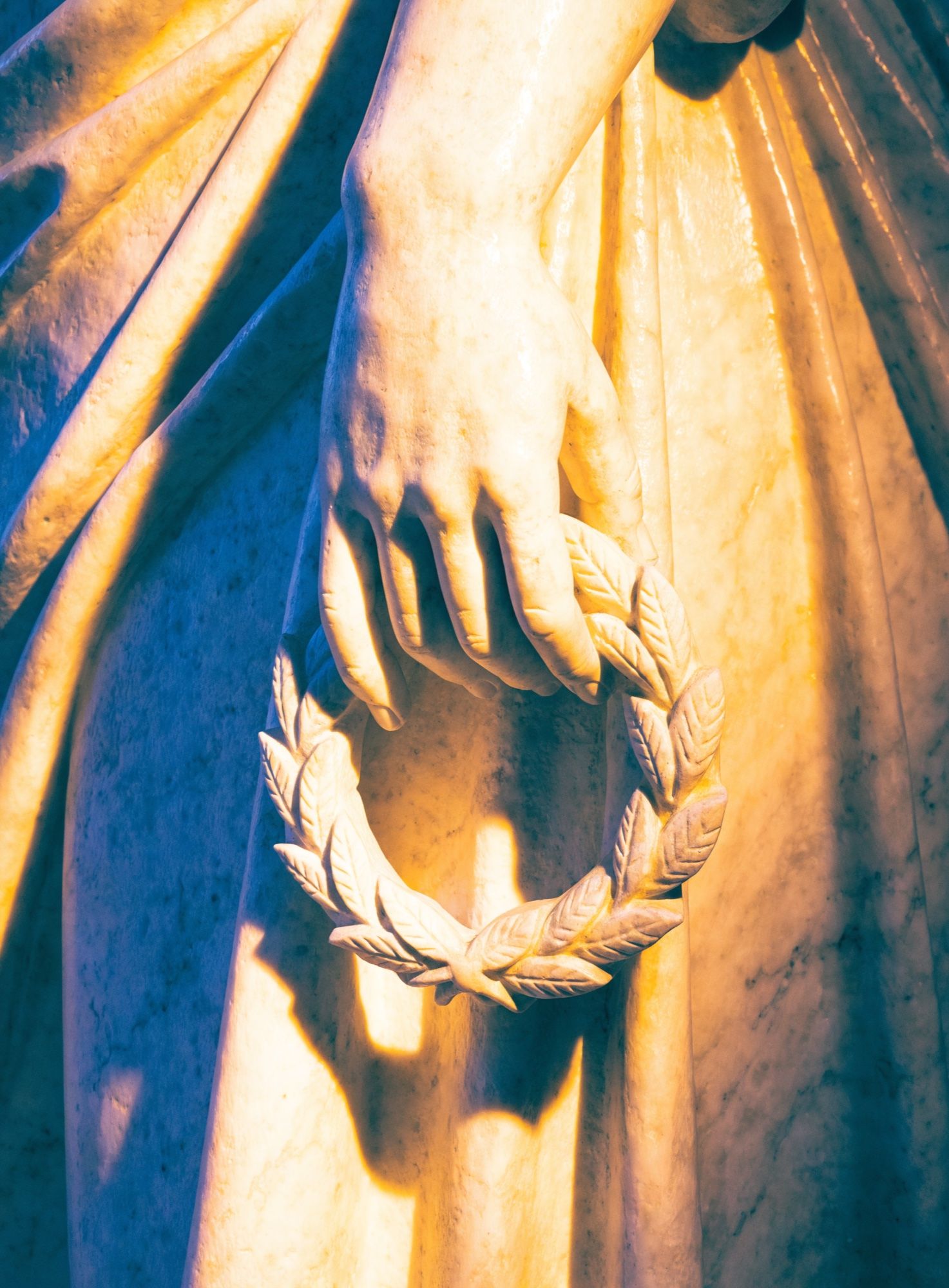 Main de statue tenant une couronne de laurier